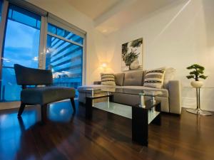 ein Wohnzimmer mit einem Sofa, einem Tisch und einem Stuhl in der Unterkunft RivetStays - The Atmos in Toronto