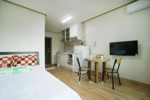 a room with a bed and a table and chairs at Sanbangsan Hot Spring Pension in Seogwipo