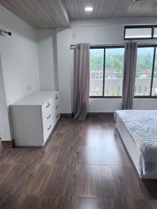 a bedroom with a bed and a dresser and windows at BKR Homestay 1BH in Itānagar