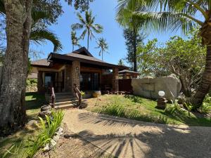 a house with palm trees in front of it at Beach Bungalow at Lanta Resort in Ko Lanta