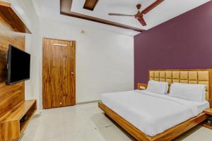 Capital O Hotel Maple View في Naroda: غرفة نوم بسرير وتلفزيون بشاشة مسطحة