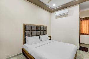 Un dormitorio blanco con una cama blanca y una ventana en Capital O Hotel Maple View, en Naroda