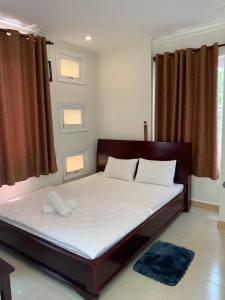 - une chambre dotée d'un grand lit avec des draps et des oreillers blancs dans l'établissement Nhu Ngoc Homestay, à Ấp Thiện Phước