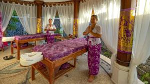 艾湄灣的住宿－巴厘島艾湄海灘棕櫚花園及Spa度假酒店，两名妇女站在一个有床的房间