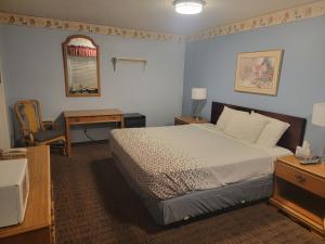 1 dormitorio con cama, escritorio y espejo en Sweet Breeze Inn, en Grants Pass