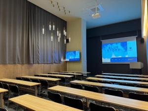 uma sala de aula com mesas e cadeiras e uma tela de projeção em Haeundae Blue Story Hotel em Busan