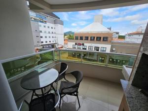 d'un balcon avec deux chaises, une table et une fenêtre. dans l'établissement Apartamento em Canasvieiras, à Florianópolis