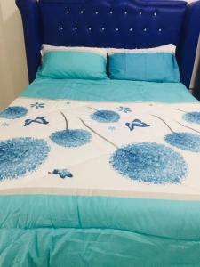 uma cama com um edredão azul e branco com sapatos em MGH Space Rental 