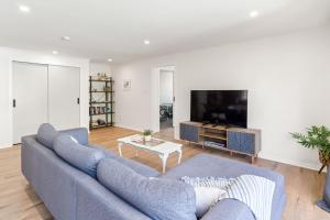 uma sala de estar com um sofá azul e uma televisão em High Street Pool House em Masterton