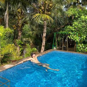 a man laying in a swimming pool in a resort at Lakefront Beach Homes in Cherai Beach