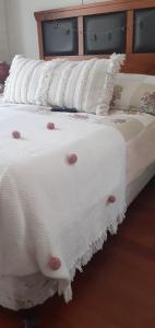 una fila de almohadas blancas sentadas en una cama en 1 habitación comoda, en Santiago