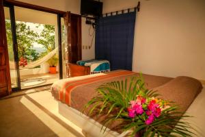 Villas Mykonos في زيبوليت: غرفة نوم بسرير ونبات ورد