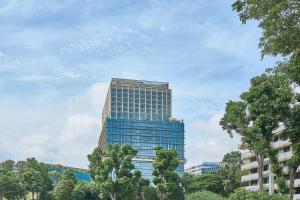 Citadines Science Park Singapore في سنغافورة: مبنى زجاجي طويل وبه اشجار امامه