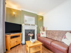 a living room with a leather couch and a fireplace at The Bungalow in Rhyl