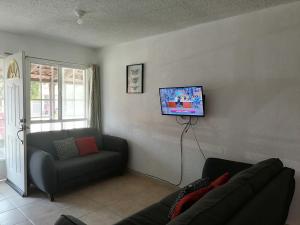 - un salon avec un canapé et une télévision murale dans l'établissement VILLAS del SEMINARIO CERCA DE ALBERCA OLIMPICA Y TEC DE MONTERREY CUERNAVACA, à Tezoyuca