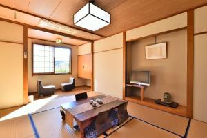 a living room with a table and a tv at 万葉茶寮みさか in Hirugami
