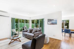 uma sala de estar com um sofá e uma mesa em Private and sunny 3-bedroom home with parking em Auckland