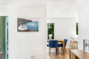 uma sala de jantar com uma mesa e um quadro na parede em Private and sunny 3-bedroom home with parking em Auckland