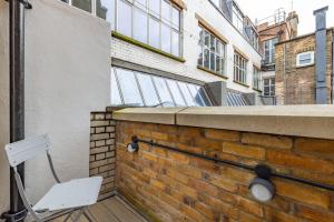 a white chair sitting on a deck next to a brick wall at Hausd - Covent Garden in London