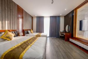 ein Hotelzimmer mit 2 Betten und einem Schreibtisch in der Unterkunft MIMOSA HOTEL in Hạ Long