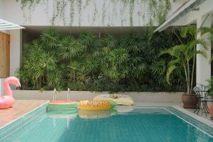 uma piscina com um macarrão de piscina em frente a uma planta em Nonnee Hotel Kata Beach Phuket em Praia de Kata