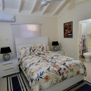a bedroom with a bed with a floral comforter at Home Away From Home in Old Harbour