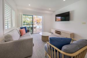 een woonkamer met een bank en een tv bij Oaks Port Stephens Pacific Blue Resort in Salamander Bay