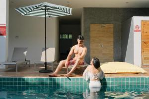 a man and woman sitting on the edge of a swimming pool at Nonnee Hotel Kata Beach Phuket in Kata Beach