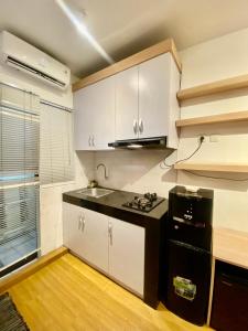 eine Küche mit weißen Schränken und einer schwarzen Arbeitsplatte in der Unterkunft Blossom Suites Bandung Cicadas at Gateway Apartment in Bandung