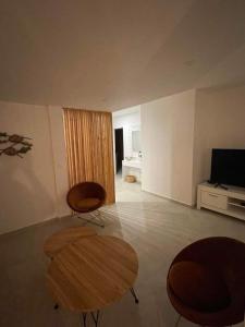 een woonkamer met 2 stoelen, een tafel en een televisie bij Coco Lodge in Les Terres Basses