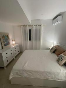 biała sypialnia z dużym łóżkiem i komodą w obiekcie Coco Lodge w mieście Les Terres Basses