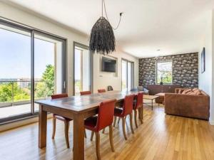 una sala da pranzo con tavolo, sedie e divano di Élégante maison à Vichy : piscine chauffée, jardin arboré, terrasse et climatisation - FR-1-489-494 a Vichy