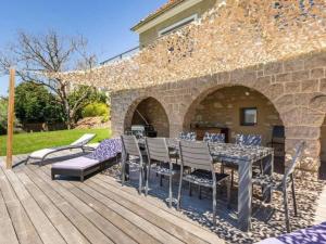 un patio con tavolo e sedie su un ponte di legno di Gîte de charme avec piscine chauffée près des thermes de Vichy, jardin clos, clim et confort absolu - FR-1-489-495 a Vichy