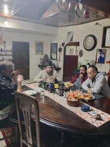 een groep mannen die rond een houten tafel zitten bij Hillgrove homestay in Kurseong