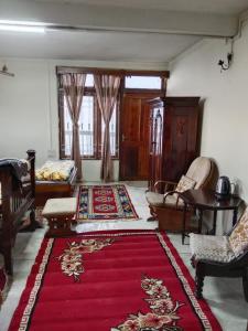een woonkamer met een rood tapijt op de vloer bij Hillgrove homestay in Kurseong