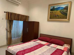 - une chambre avec un lit et une peinture murale dans l'établissement Sinergi Hotel Tretes, à Pasuruan