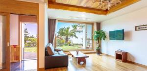 a living room with a couch and a large window at Harmony Resort in Jeju