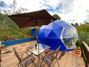 a table and chairs with an umbrella on a deck at Glamping blue. in Guatavita