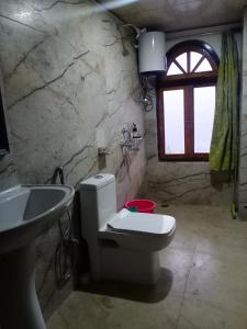 a bathroom with a toilet and a sink and a window at Daragaon Retreat (Gurung Homestay) in Pelling