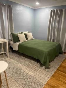 Schlafzimmer mit einem Bett mit grüner Bettwäsche und Kissen in der Unterkunft Bluebird Abode Stand Alone House 3 Bed 2 Full Bath in Chattanooga