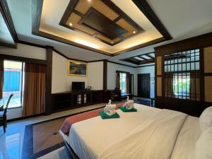 a bedroom with a large bed with two towels at Beach Bungalow at Lanta Resort in Ko Lanta