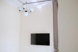 a living room with a tv and a white wall at Kays Homestay Jogja in Ngemplak