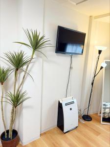 a room with two palm trees and a tv on a wall at 道頓堀House in Osaka