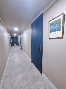 um corredor vazio com uma porta azul e um quadro na parede em Taereung stay em Seul