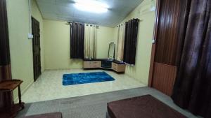 sala de estar con TV y alfombra azul en Nik Legacy Homestay en Pasir Puteh