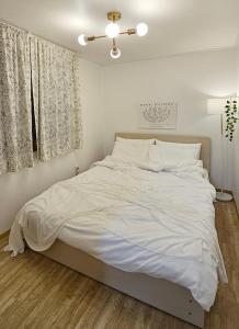 um quarto com uma cama grande e lençóis brancos em Hue Stay Hongdae em Seul