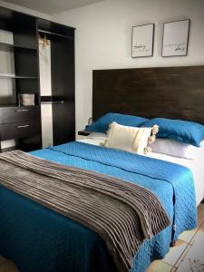 a bedroom with a large bed with blue sheets at Cozy PH Apartment in the City in Guatemala