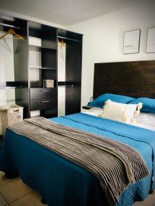 a bedroom with a blue bed with a black headboard at Cozy PH Apartment in the City in Guatemala