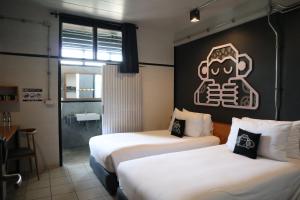 2 Betten in einem Zimmer mit Schild an der Wand in der Unterkunft Blu Monkey Hub & Hotel Surat Thani in Surat Thani
