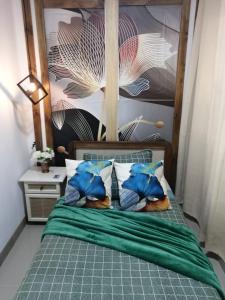 1 cama con edredón verde y almohadas azules en Cabañas Mantas, en Tarcoles